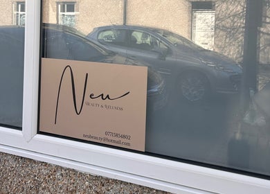 Exterior view of Neu Beauty Salon, Newport, Wales, GB featuring elegant signage on window.