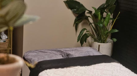 Inviting treatment room with cozy bedding and lush plant at Bee Revived, Manchester, England, GB.