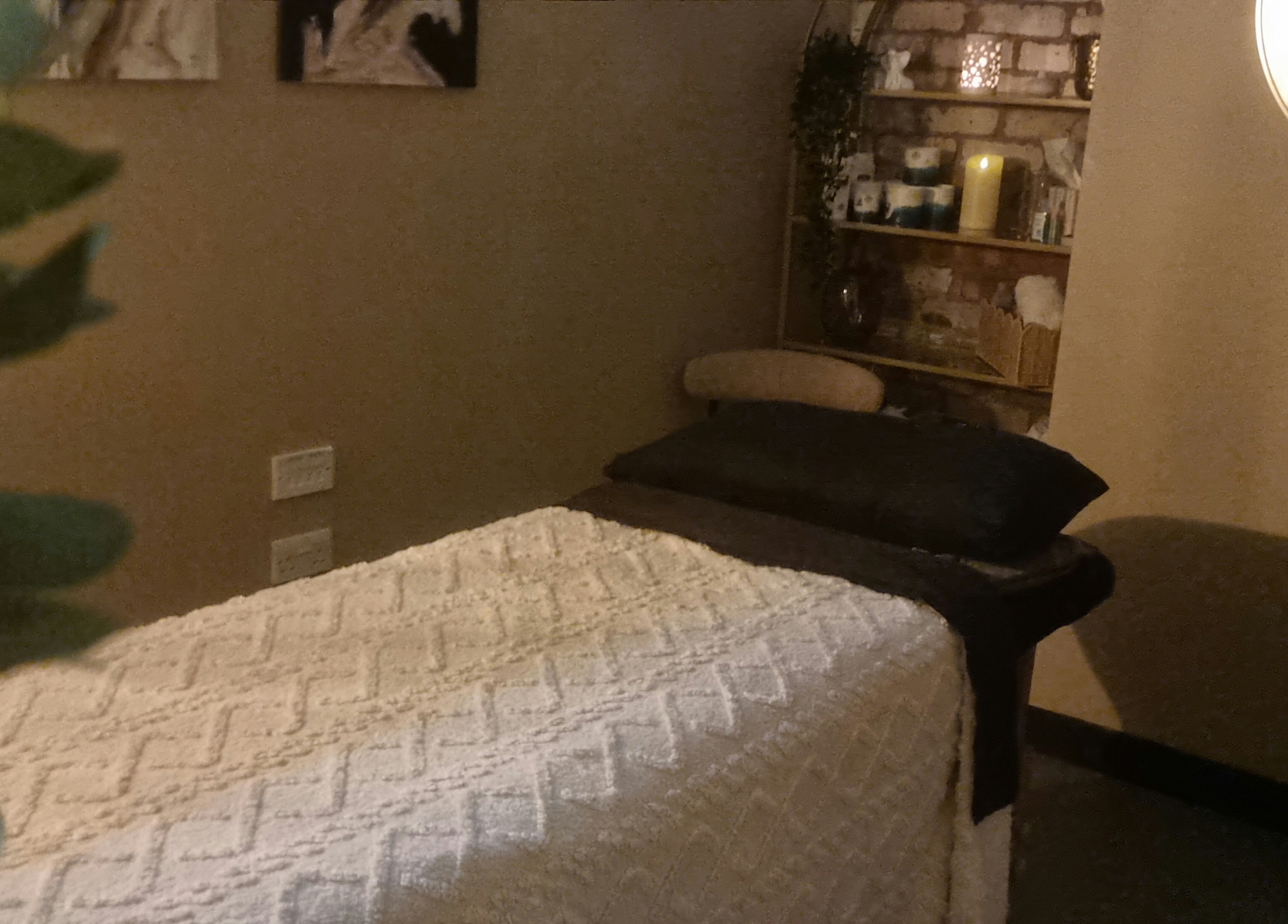 Cozy massage room at Bee Revived, with a soft bed, plants, and warm lighting in Manchester, England, GB.
