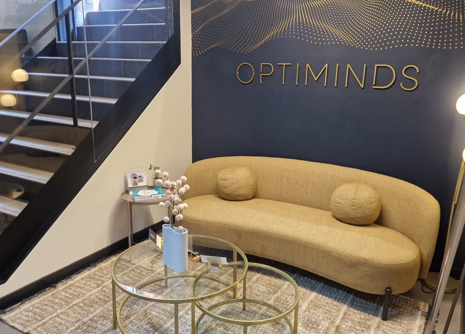 Elegant waiting area with gold couch at Bee Revived, Manchester, England, GB, under a modern staircase.