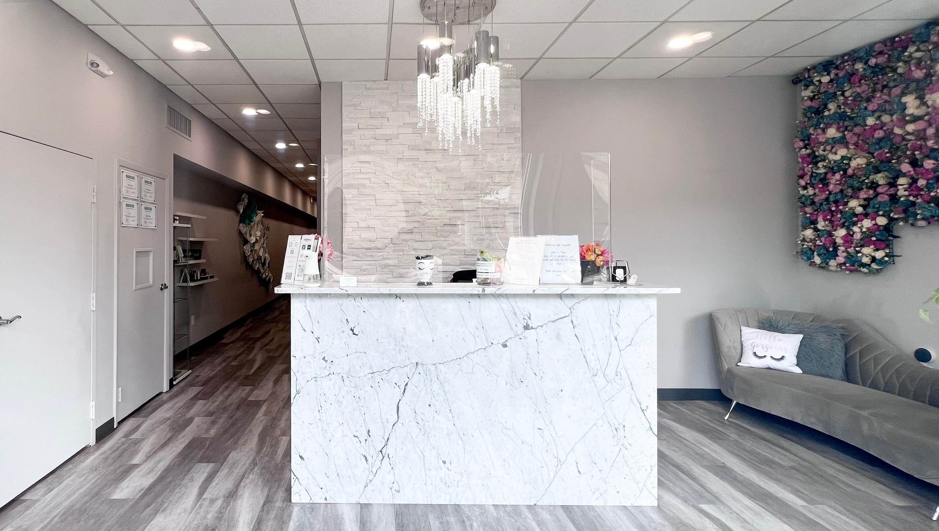 Reception area of Lashes by Katie and Skincare, Bethesda, Maryland, US. Features a marble desk and chic decor.