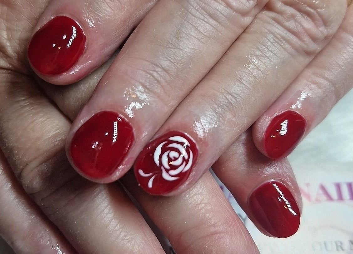 Close-up of red nails with a white rose design at Fantasy Nails, Holyhead, Cymru, GB.