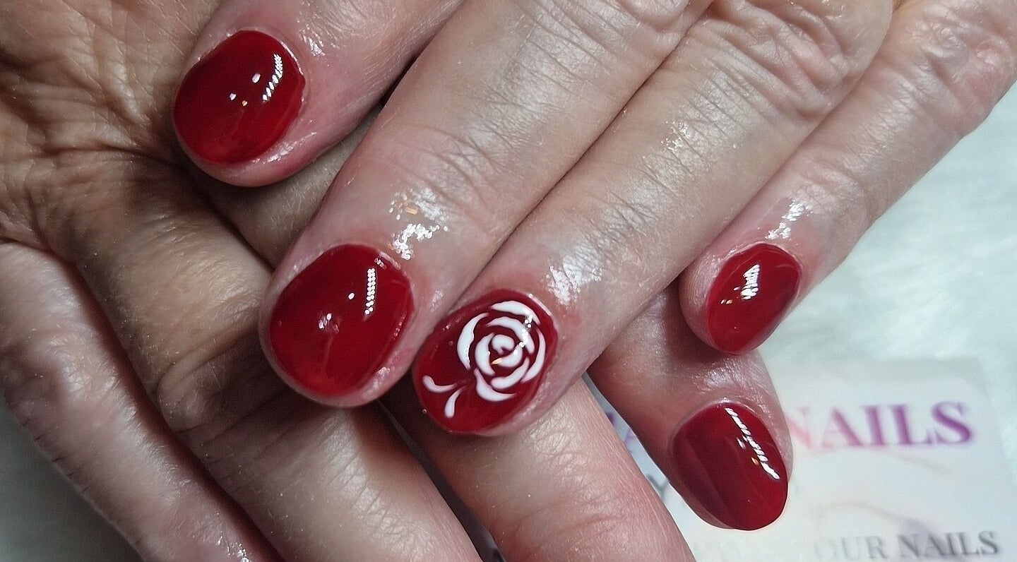 Close-up of red nails with a white rose design at Fantasy Nails, Holyhead, Cymru, GB.