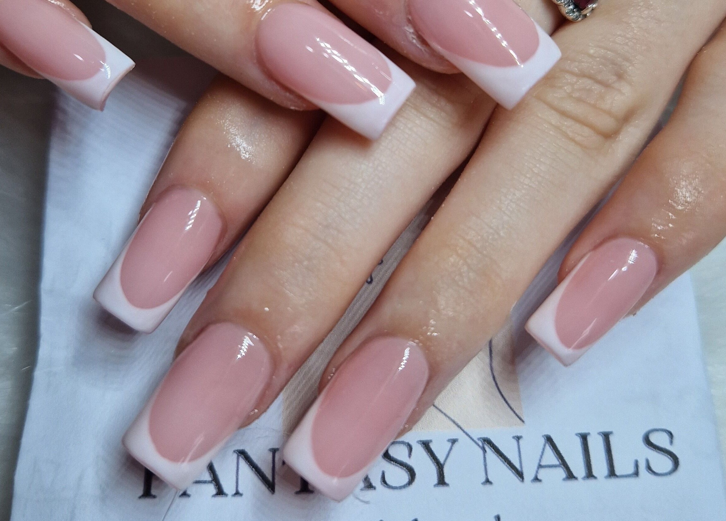 Elegant French manicure at Fantasy Nails in Holyhead, Cymru, GB, showcasing glossy pink and white tip design.