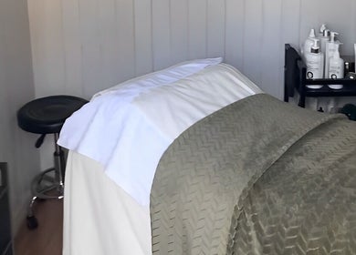 Spa room at Livella Skin in Chester, England featuring a treatment bed with soft linens and skincare products.