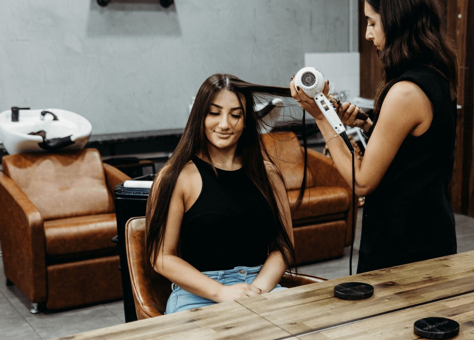Stylist blow-drying client's hair at Soho Hair Salon in Narellan, New South Wales, AU.
