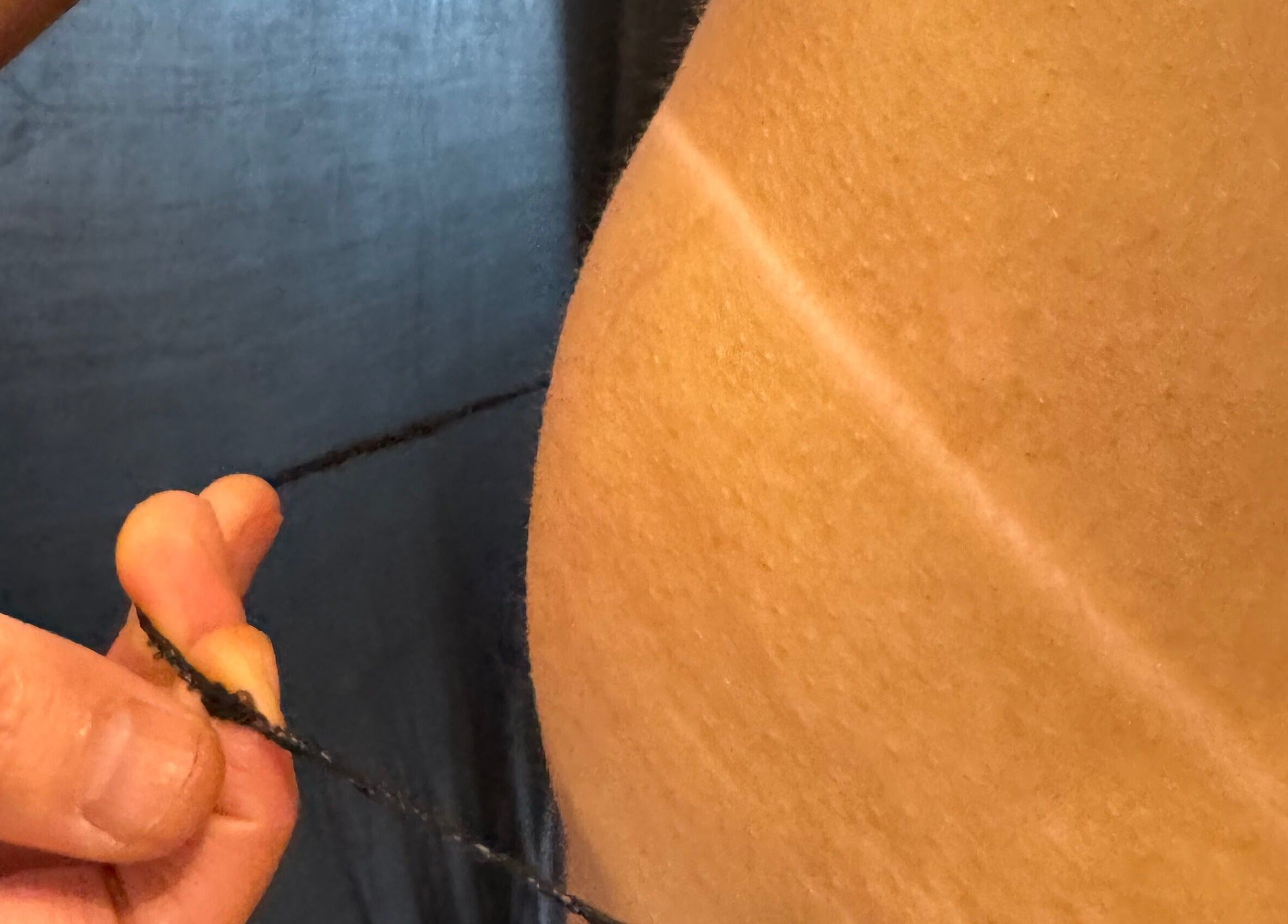 Hand holding threading string for brow shaping at Kanti Studio, Colwick, England, GB.