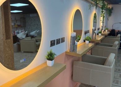 Elegant salon interior at Preston & Co Hairdressing, Clayton-le-woods, England, GB with chic round mirrors and greenery.