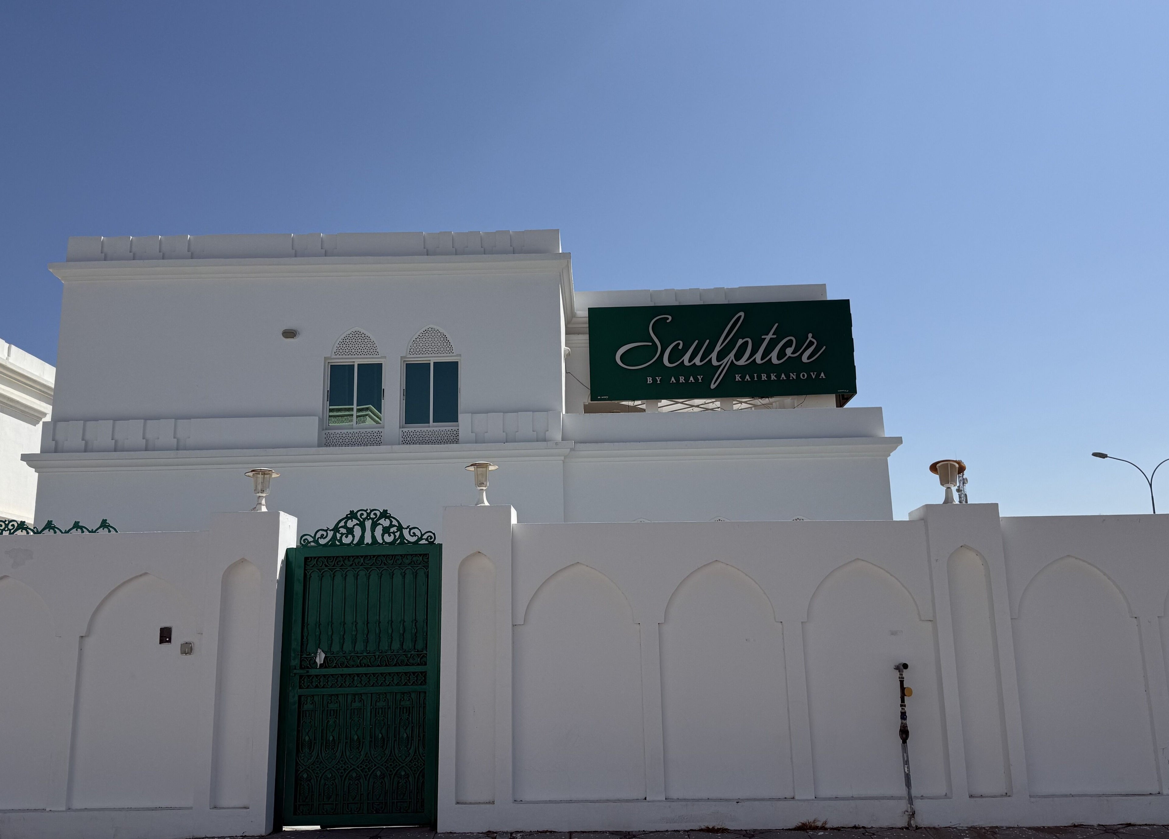 Elegant facade of Sculptor by Aray Kairkanova in Muscat, Muscat Governorate, OM under a clear blue sky.