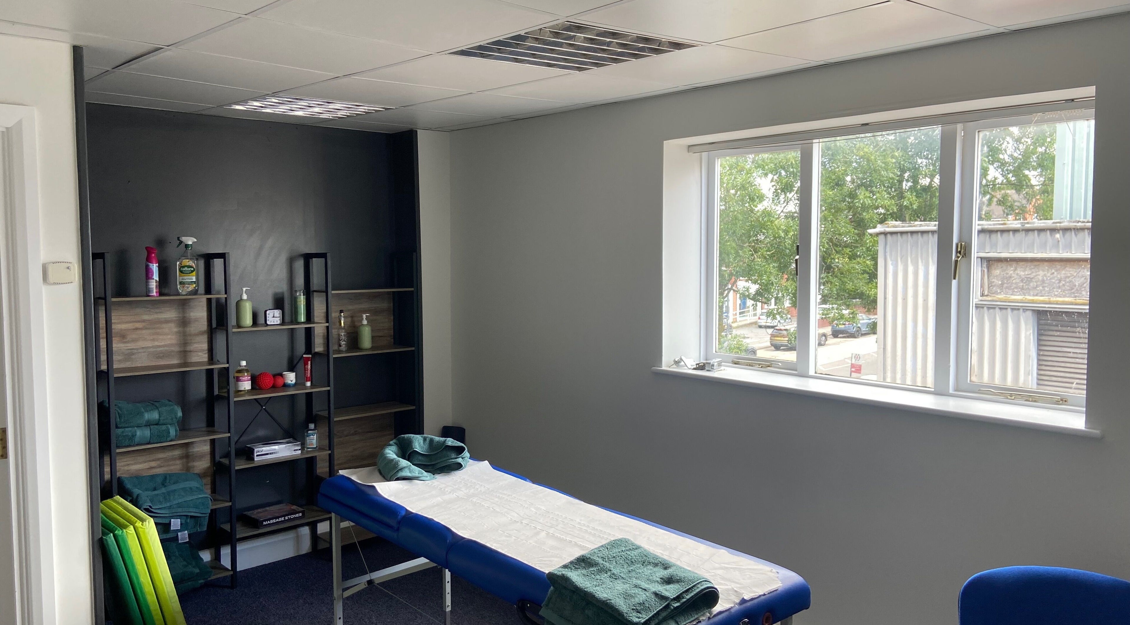 Relaxing therapy room at Y. T. Sports Therapy, Walsall Wood, England, GB with massage table and shelves with supplies.