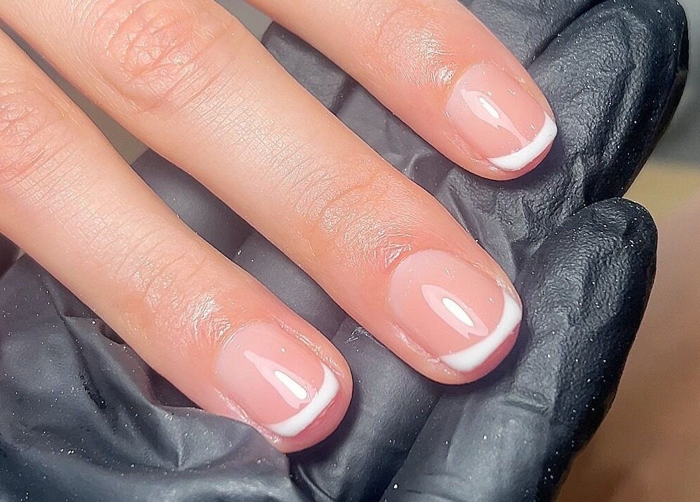 Close-up of French manicure at MAUDÉ Studio in Bassingbourn, England, GB, showing polished elegance.