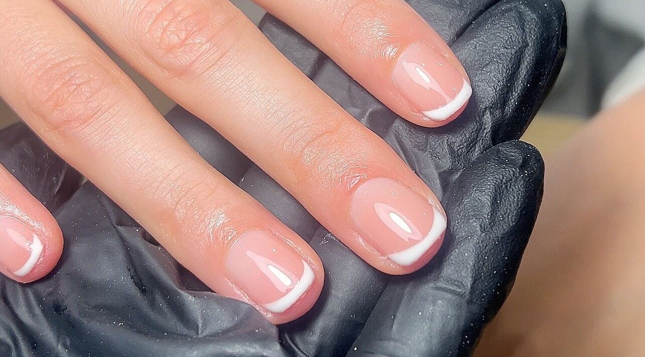 Close-up of French manicure at MAUDÉ Studio in Bassingbourn, England, GB, showing polished elegance.