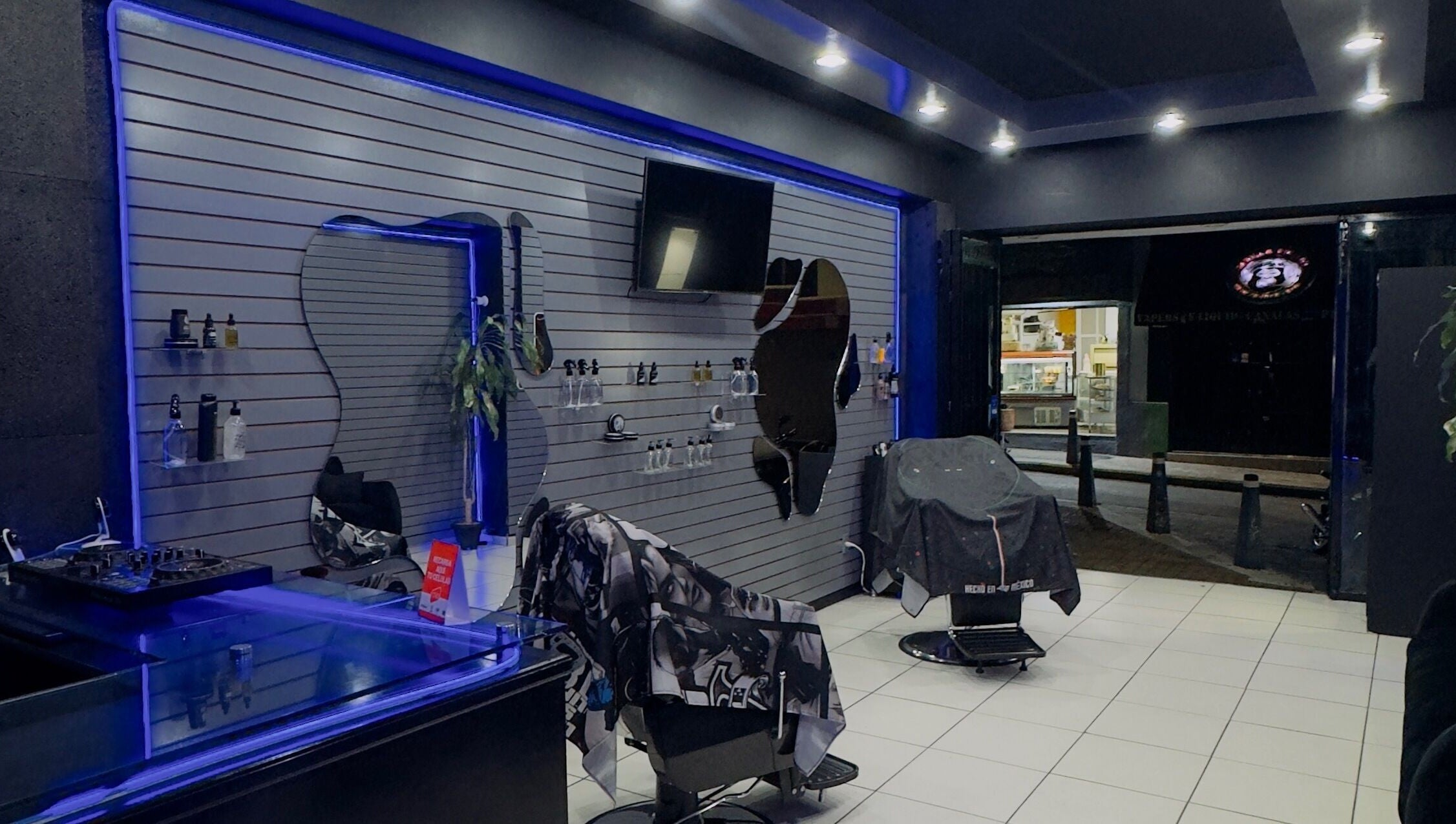 Sleek interior of Barberia Mercurio in Zapopan, Jalisco, MX; features stylish chairs and ambient lighting.