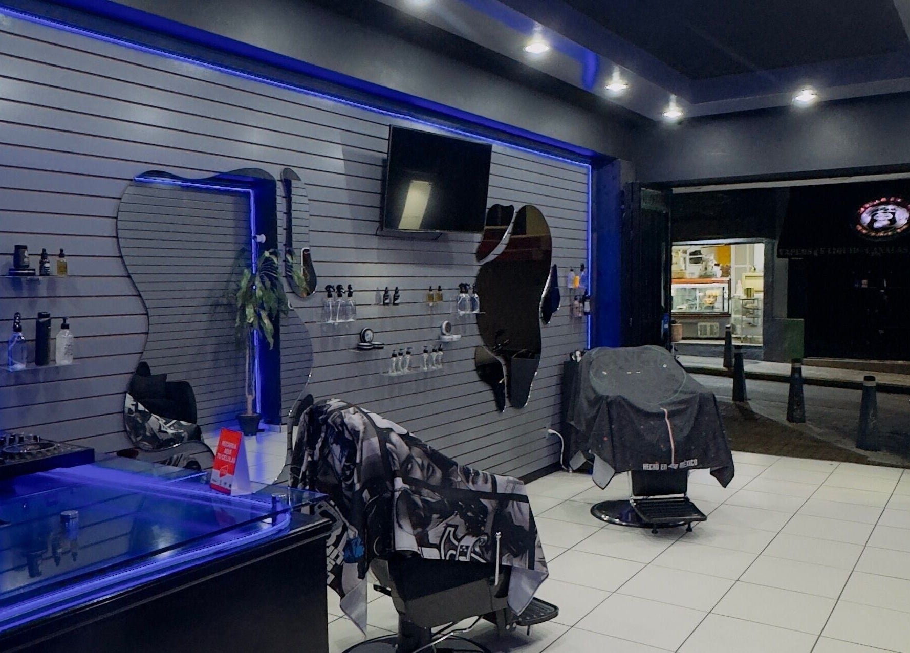 Sleek interior of Barberia Mercurio in Zapopan, Jalisco, MX; features stylish chairs and ambient lighting.