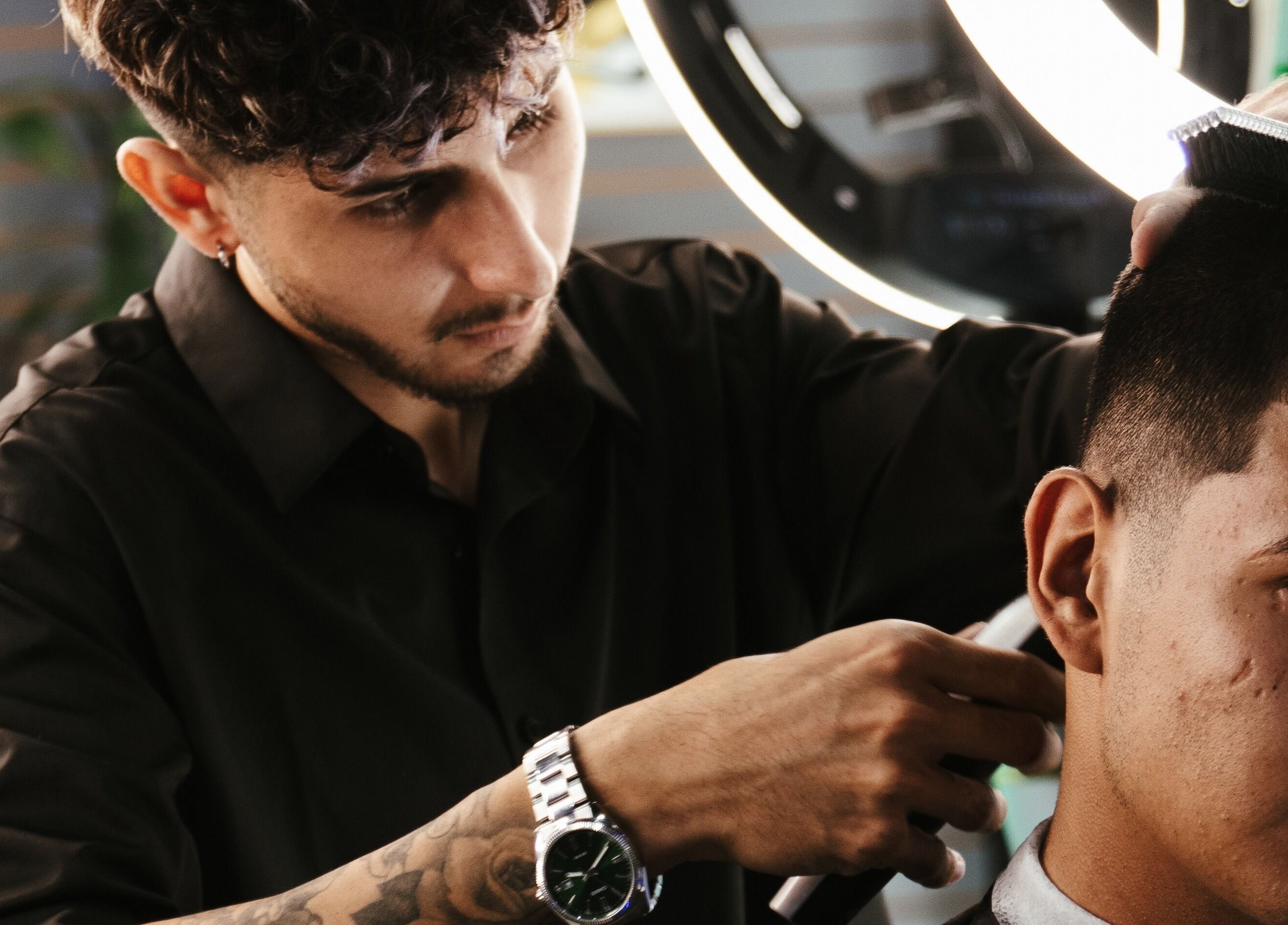 Stylist at Barberia Mercurio expertly cutting hair, Zapopan, Jalisco, MX, under warm salon lighting.