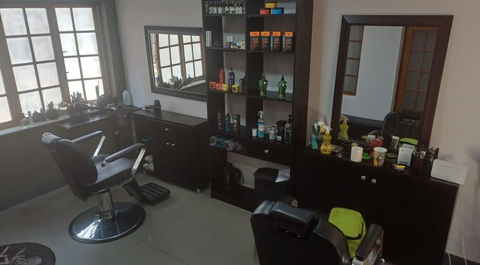 Interior of Meneer Barbershop in Boksburg, Gauteng, ZA featuring modern barber chairs and product display.
