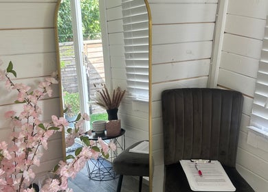 Cozy corner at Maisy’sBeautyBarn, Headcorn, England, with mirror, chair, and floral decor.