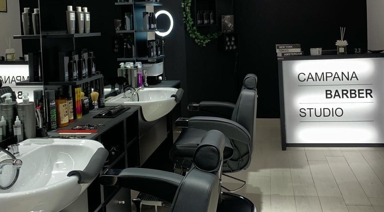 Interno moderno di CAMPANA BARBER STUDIO, Andria, Puglia, IT con sedie eleganti e prodotti per capelli.