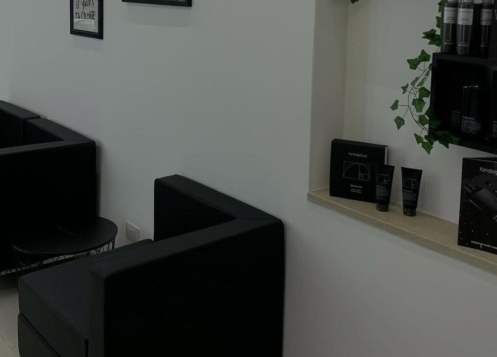 Interno elegante di CAMPANA BARBER STUDIO a Andria, Puglia, IT con arredi neri e prodotti su mensola.