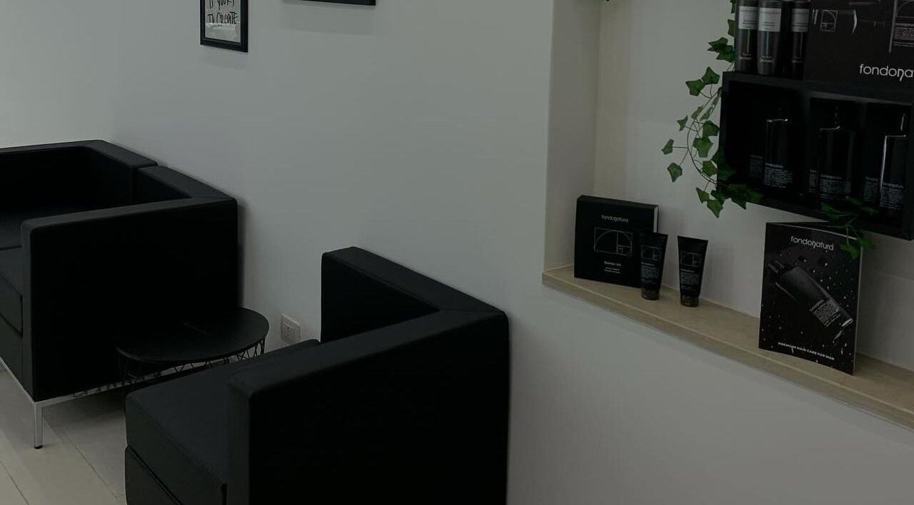 Interno elegante di CAMPANA BARBER STUDIO a Andria, Puglia, IT con arredi neri e prodotti su mensola.