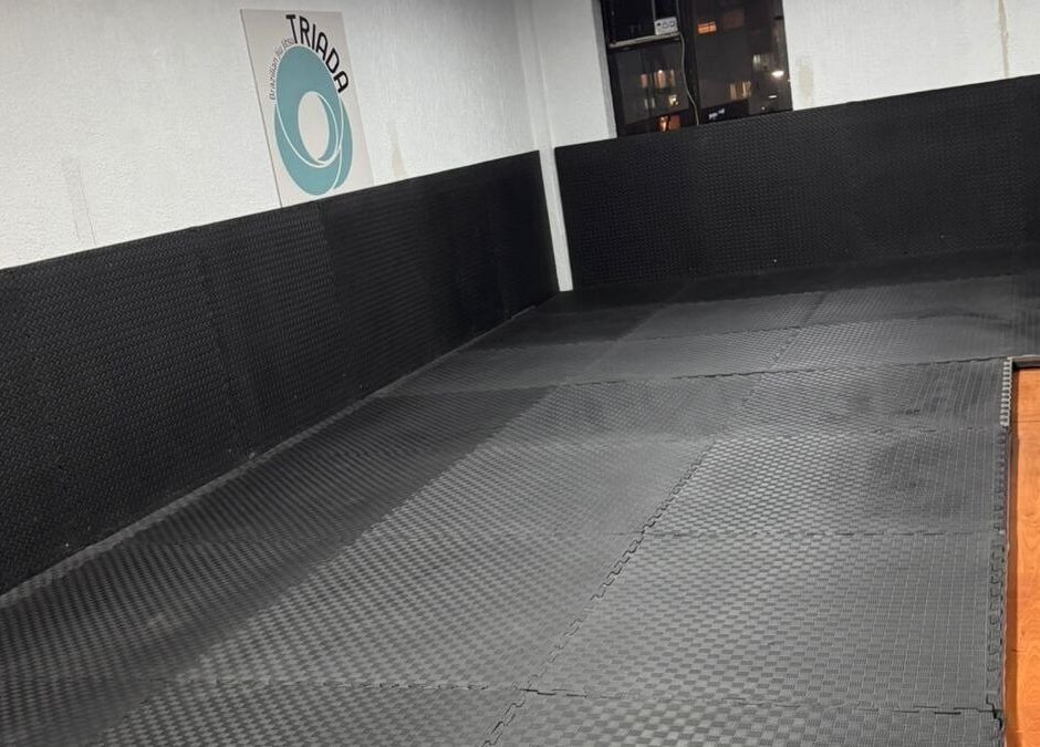 Área de entrenamiento en Triada Jiu Jitsu, Ñuñoa, Región Metropolitana, CL, con tatamis negros.