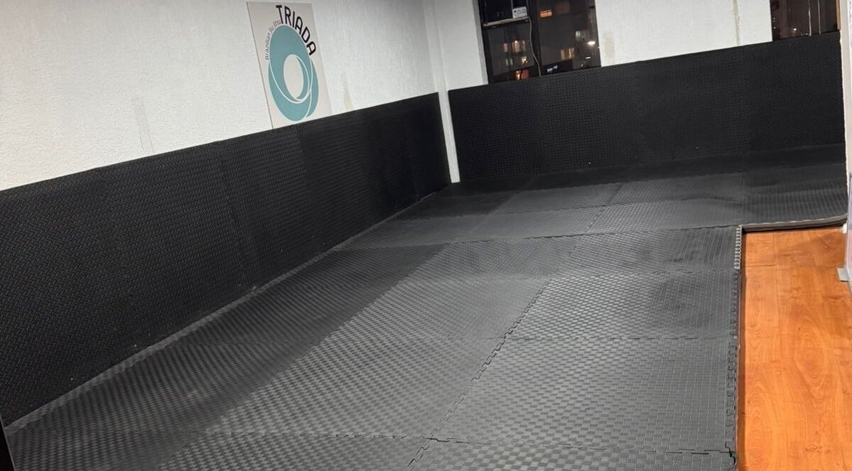 Área de entrenamiento en Triada Jiu Jitsu, Ñuñoa, Región Metropolitana, CL, con tatamis negros.
