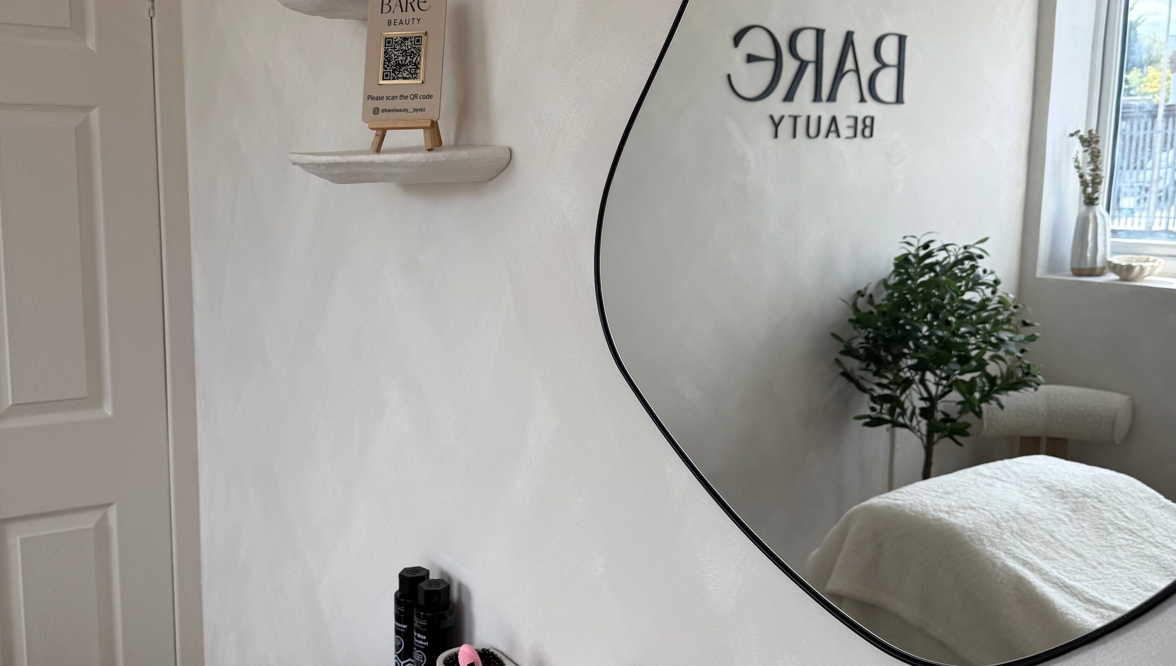 Elegant spa mirror reflects the calming interior of Bare Beauty by Vici in Andover, England, GB.
