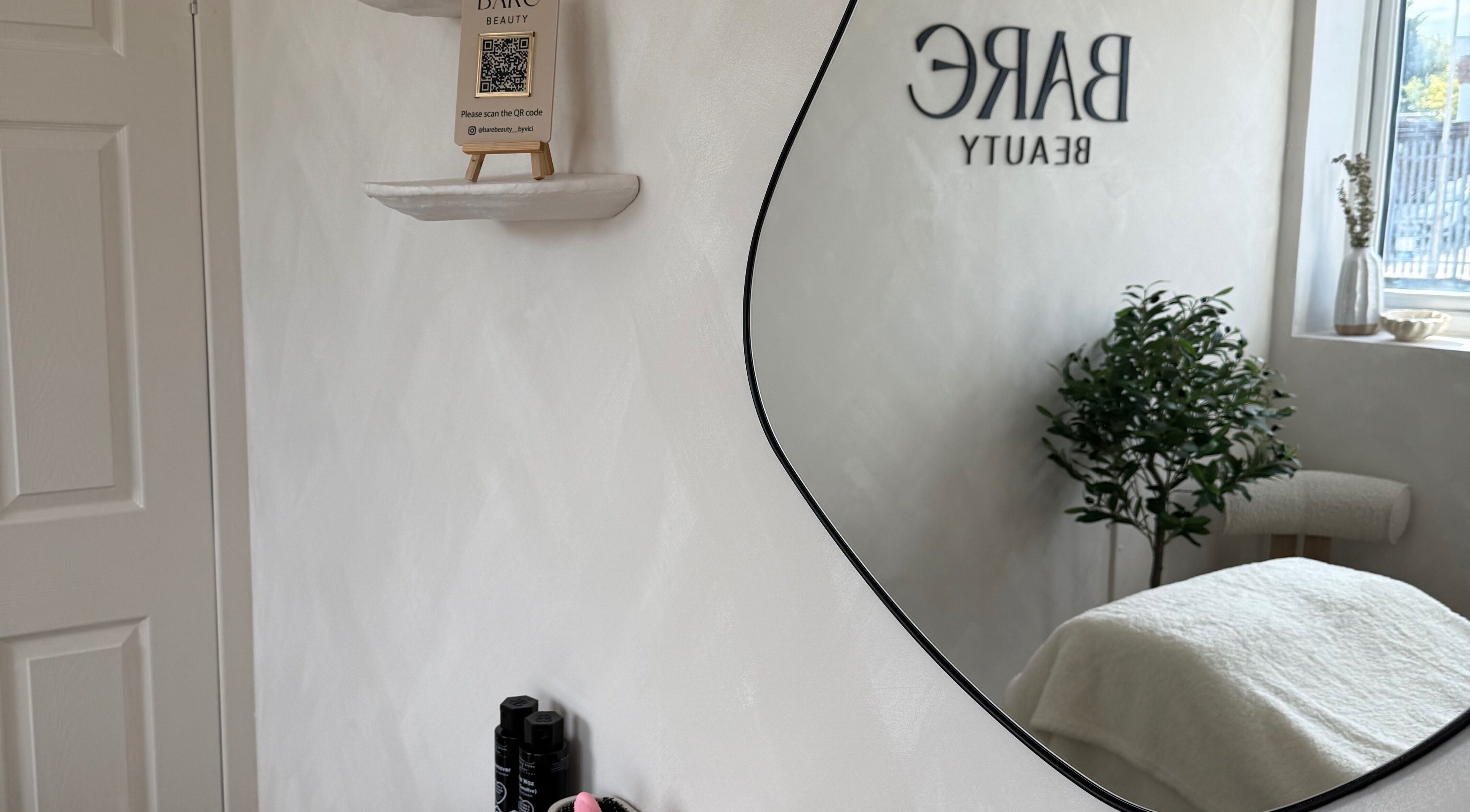 Elegant spa mirror reflects the calming interior of Bare Beauty by Vici in Andover, England, GB.