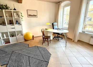 Bureau lumineux au MTC Eglantine, Morges, Vaud, CH. Intérieur avec fauteuil, table, étagères blanches.