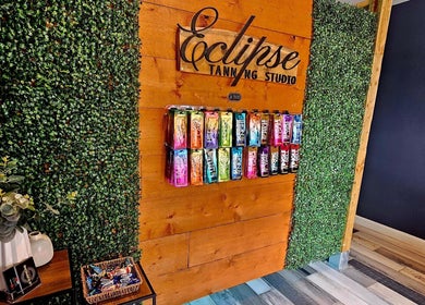 Colorful product display at Eclipse Tanning Studio, Launceston, Cornwall, GB, framed by lush greenery.