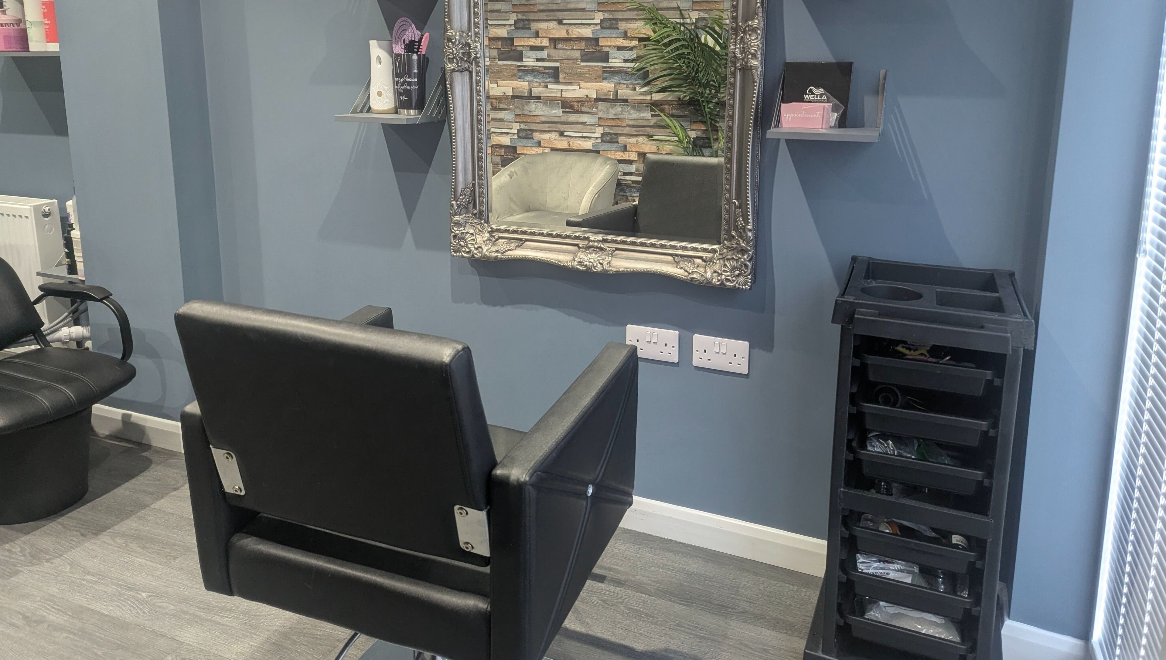 Chic salon interior at Hair By Mia in Carlisle, England, featuring a modern styling chair and ornate mirror.