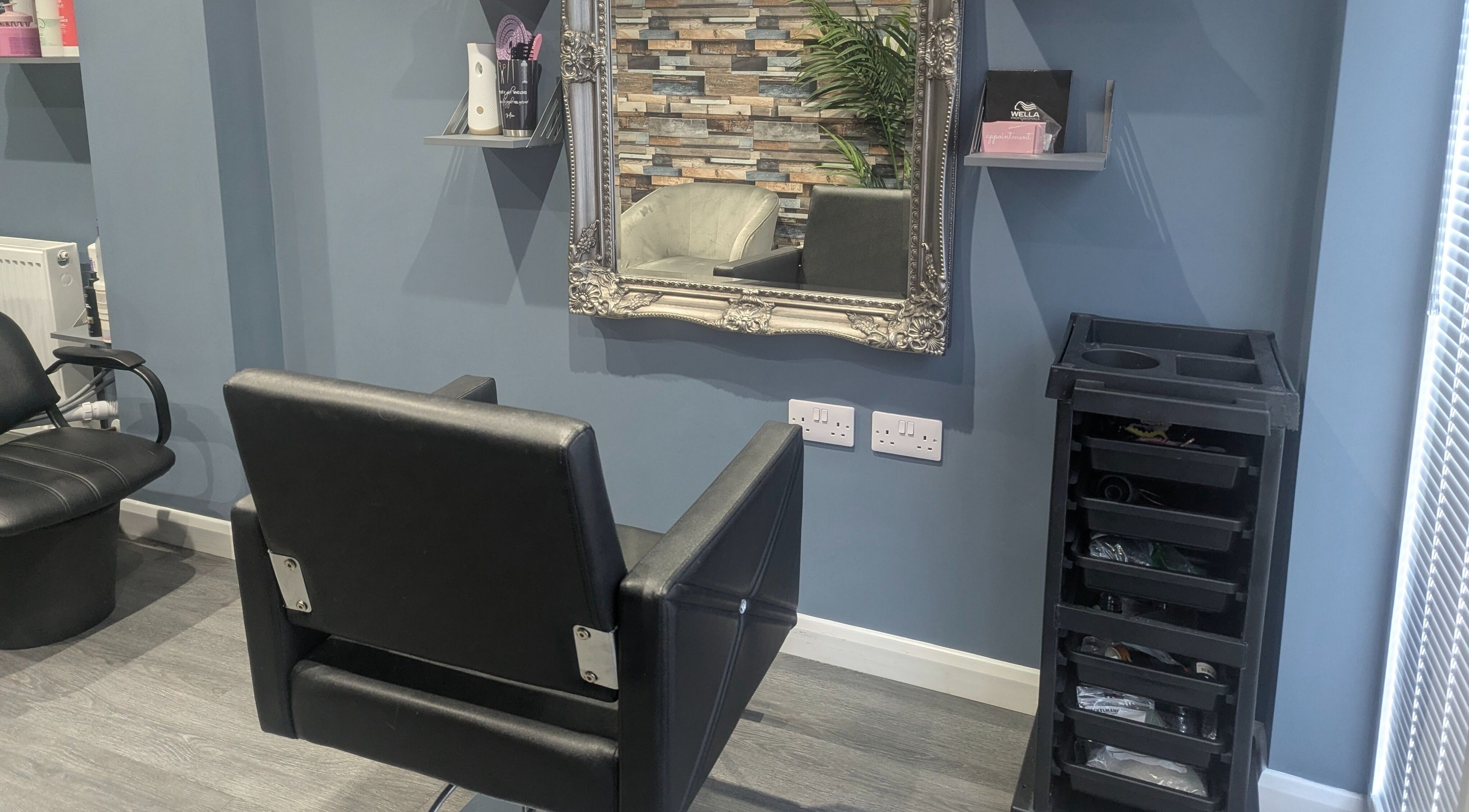 Chic salon interior at Hair By Mia in Carlisle, England, featuring a modern styling chair and ornate mirror.
