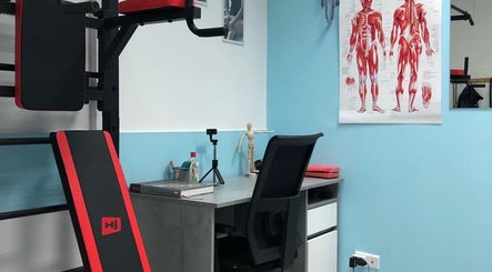 Кабинет IDMassage в Варшаве с анатомическим плакатом и тренажером.