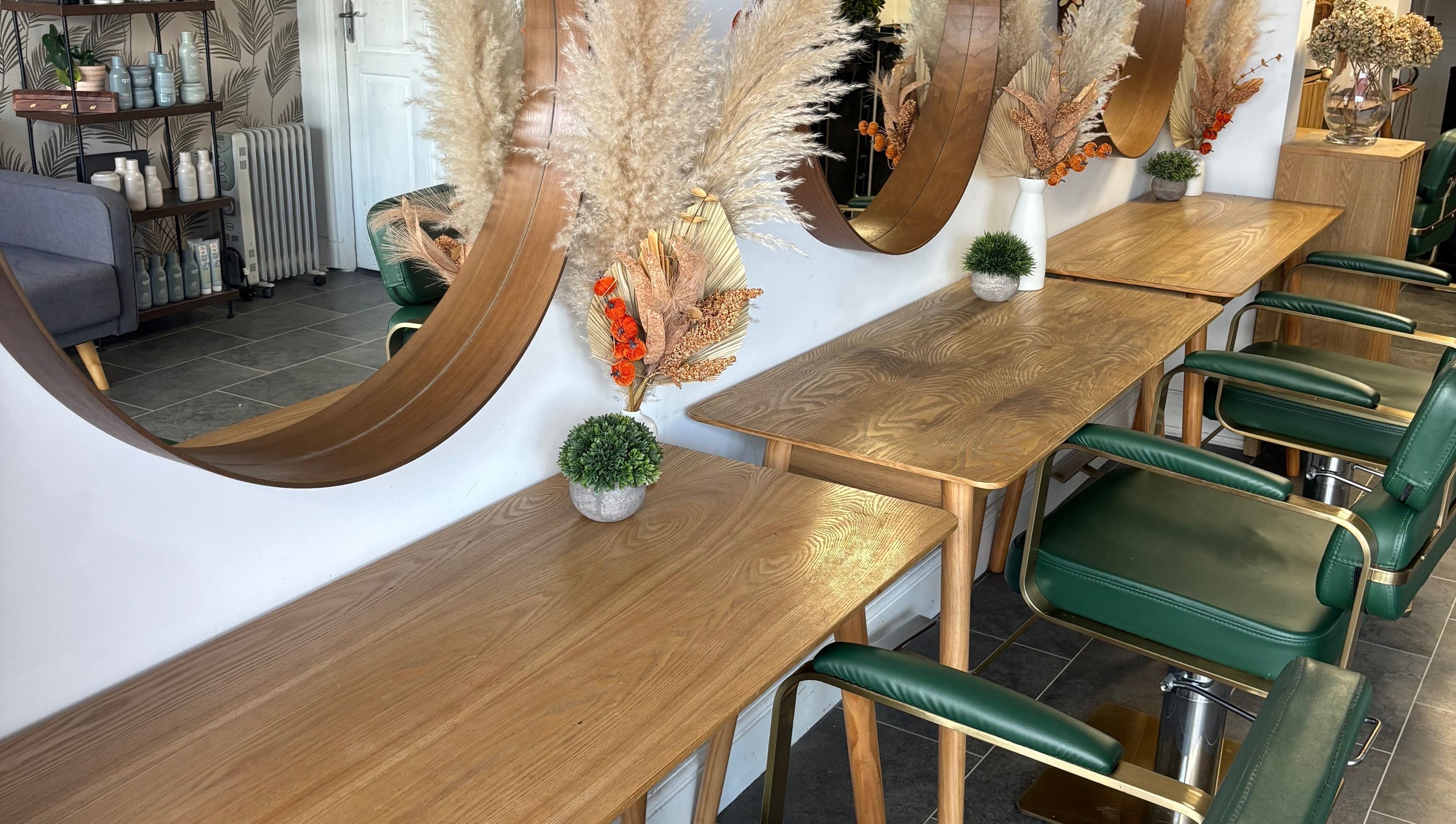 Perfection salon in Swindon, England, GB features stylish wooden tables and mirrors with green chairs.