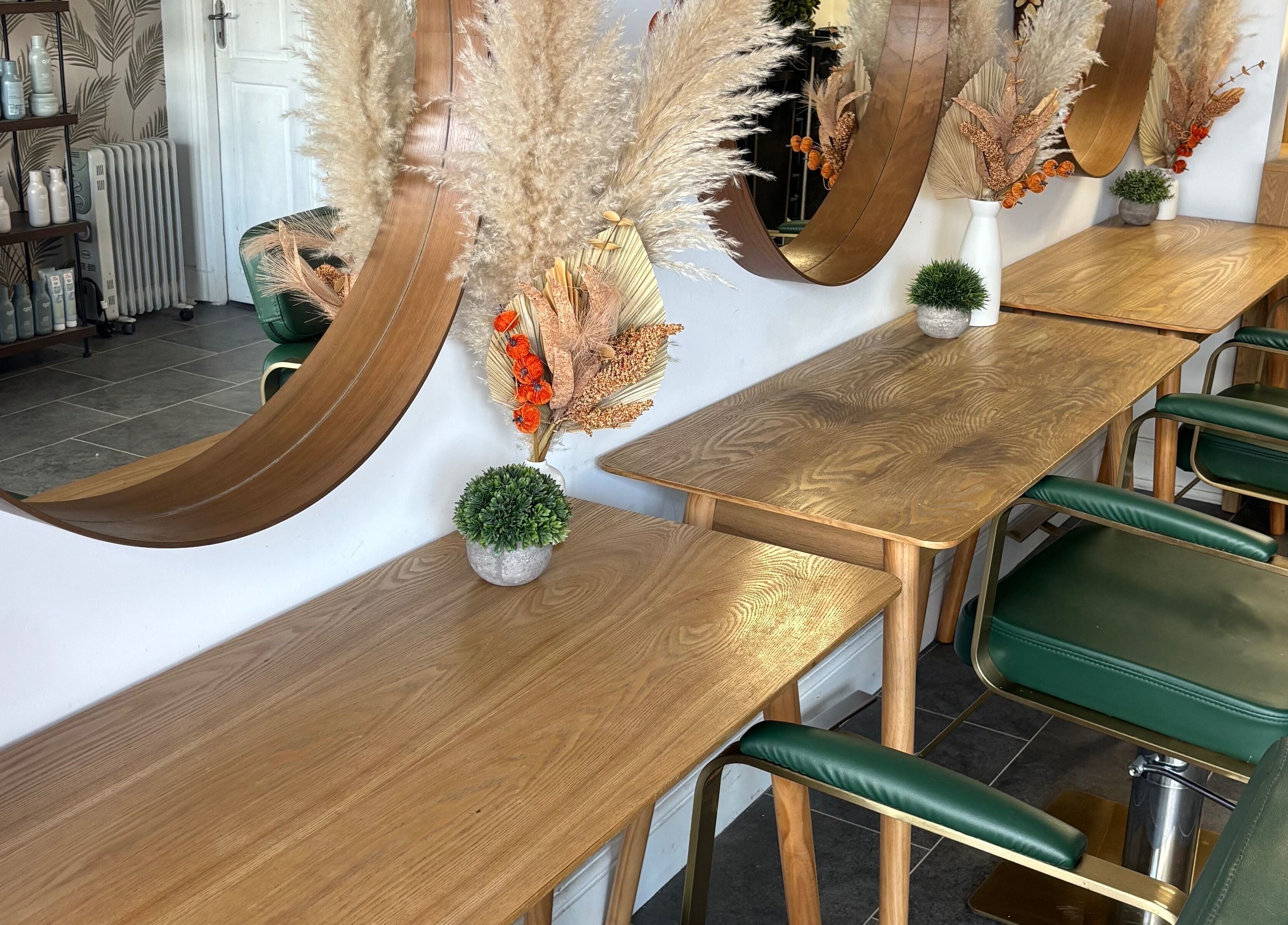 Perfection salon in Swindon, England, GB features stylish wooden tables and mirrors with green chairs.