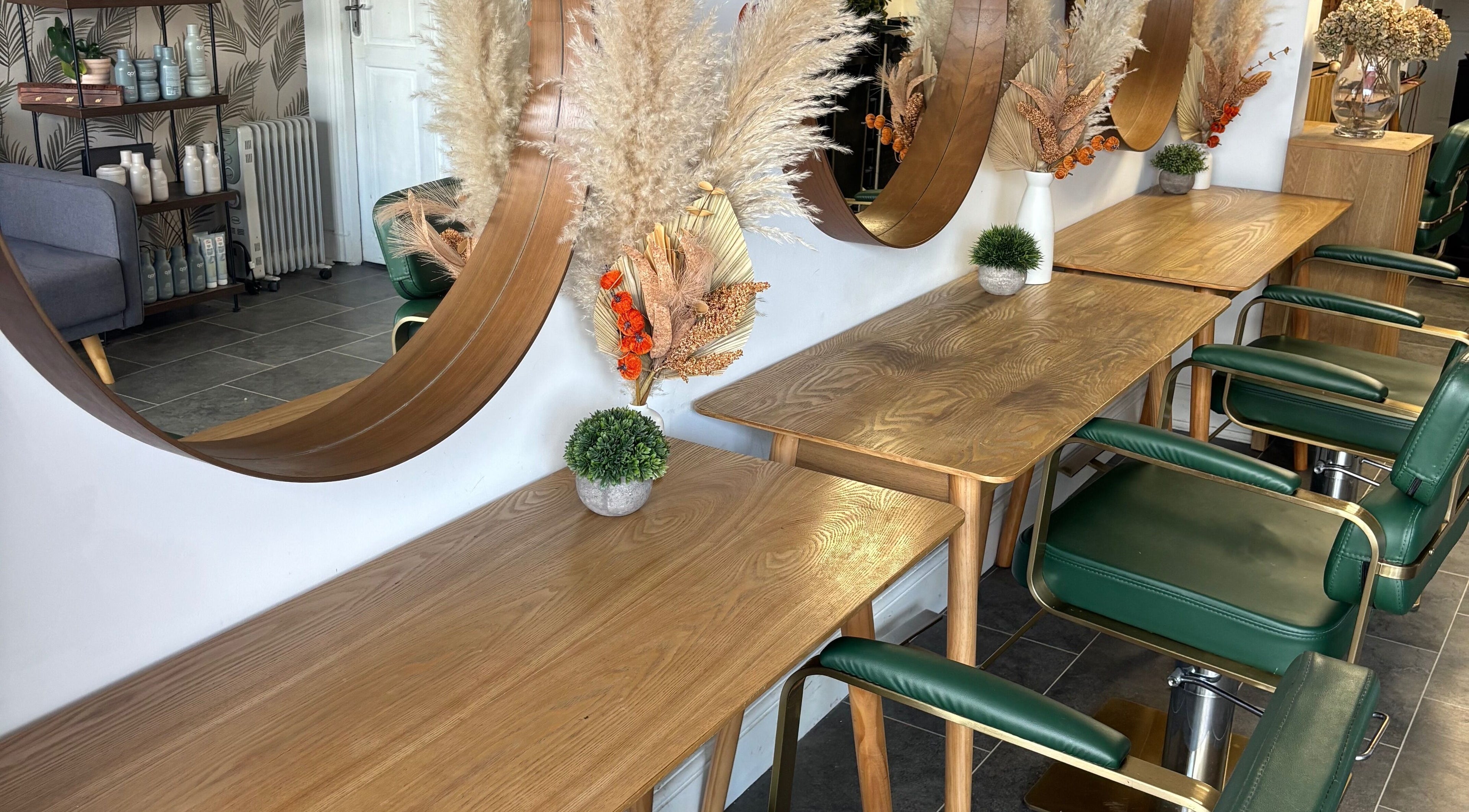 Perfection salon in Swindon, England, GB features stylish wooden tables and mirrors with green chairs.
