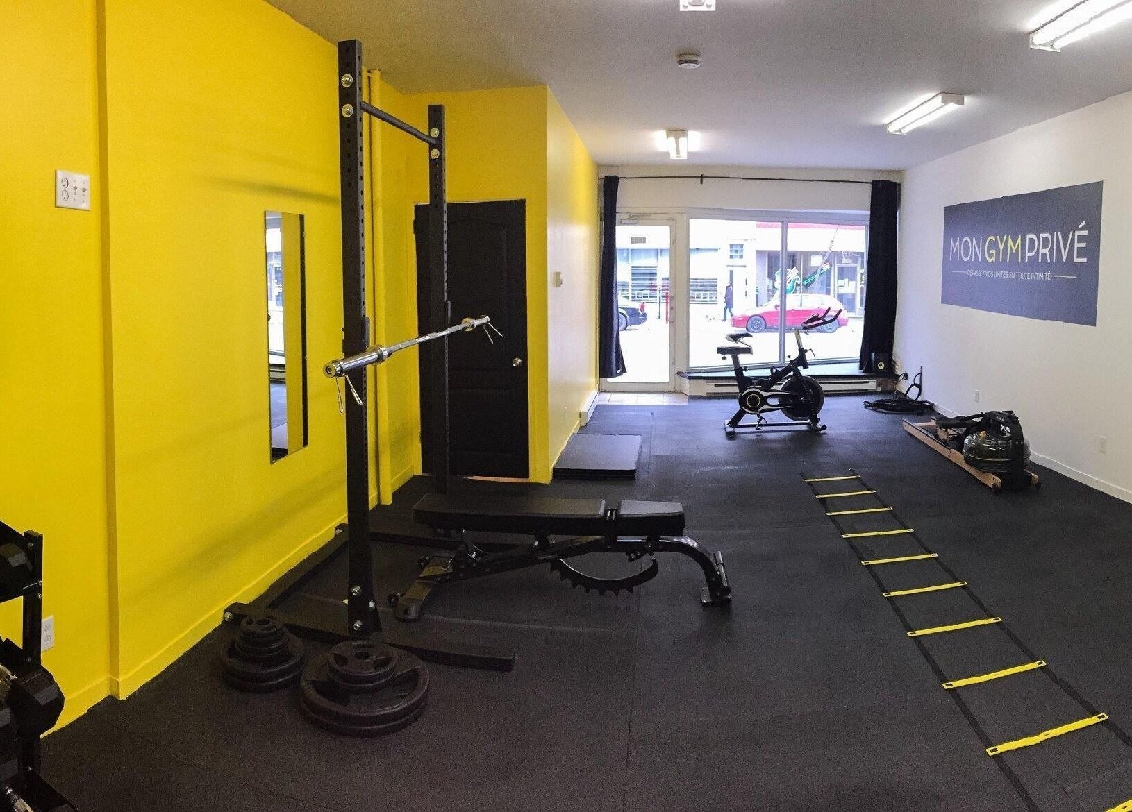 Salle de gym moderne à MON GYM PRIVÉ, Montréal, Québec, CA avec équipements d'exercice et murs jaunes.