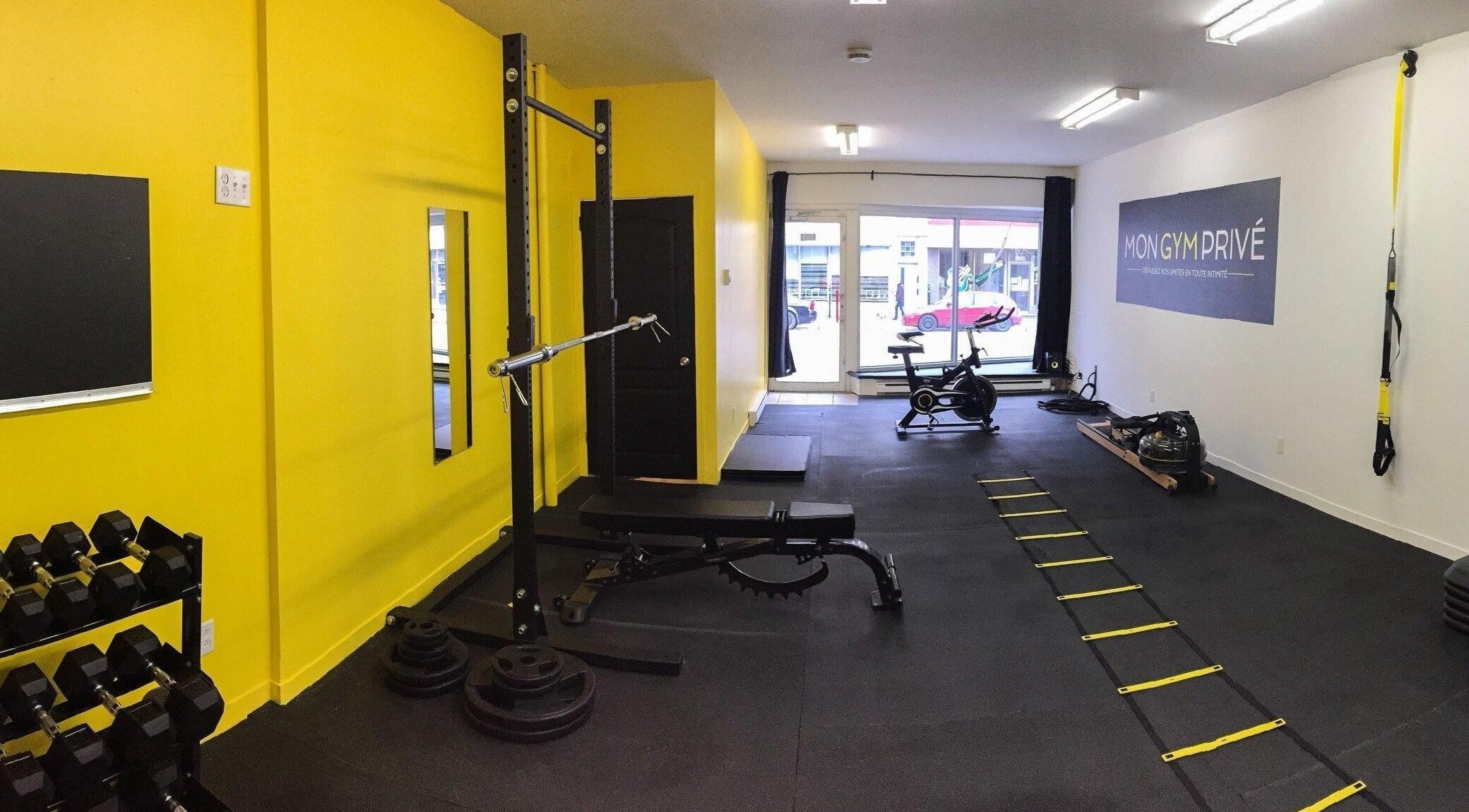 Salle de gym moderne à MON GYM PRIVÉ, Montréal, Québec, CA avec équipements d'exercice et murs jaunes.