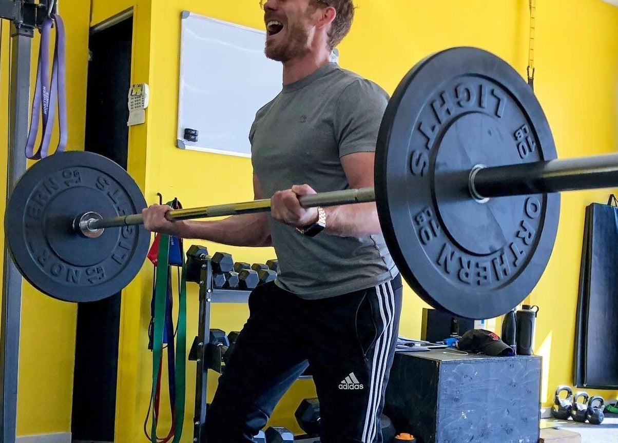 Homme soulevant des poids à MON GYM PRIVÉ, Montréal, Québec, CA, dans une salle à mur jaune.