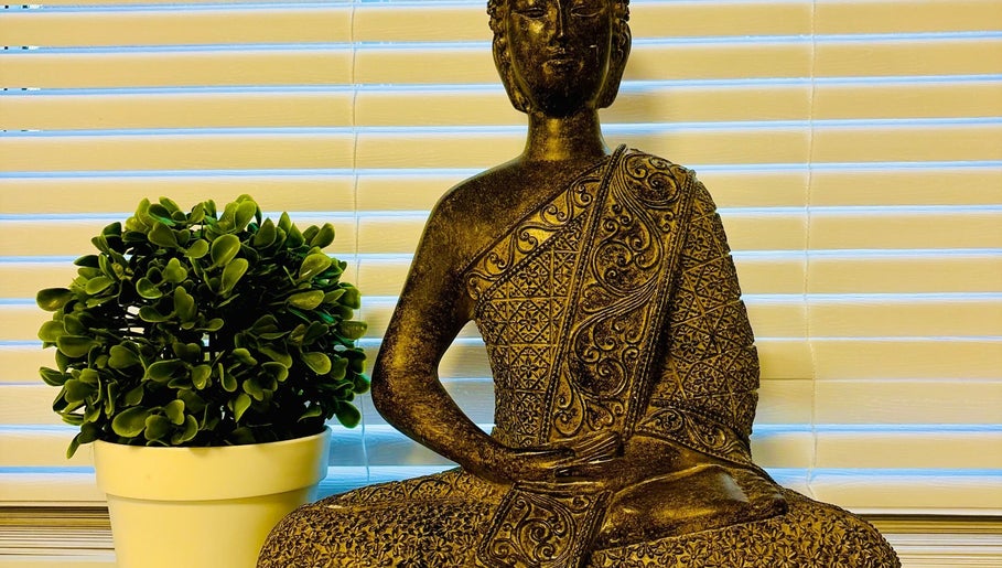 Peaceful Buddha statue at Anna Massage Therapy & Spa, Newcastle upon Tyne, England, GB, with lush green plant.
