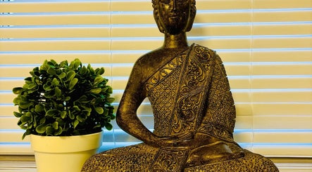 Peaceful Buddha statue at Anna Massage Therapy & Spa, Newcastle upon Tyne, England, GB, with lush green plant.