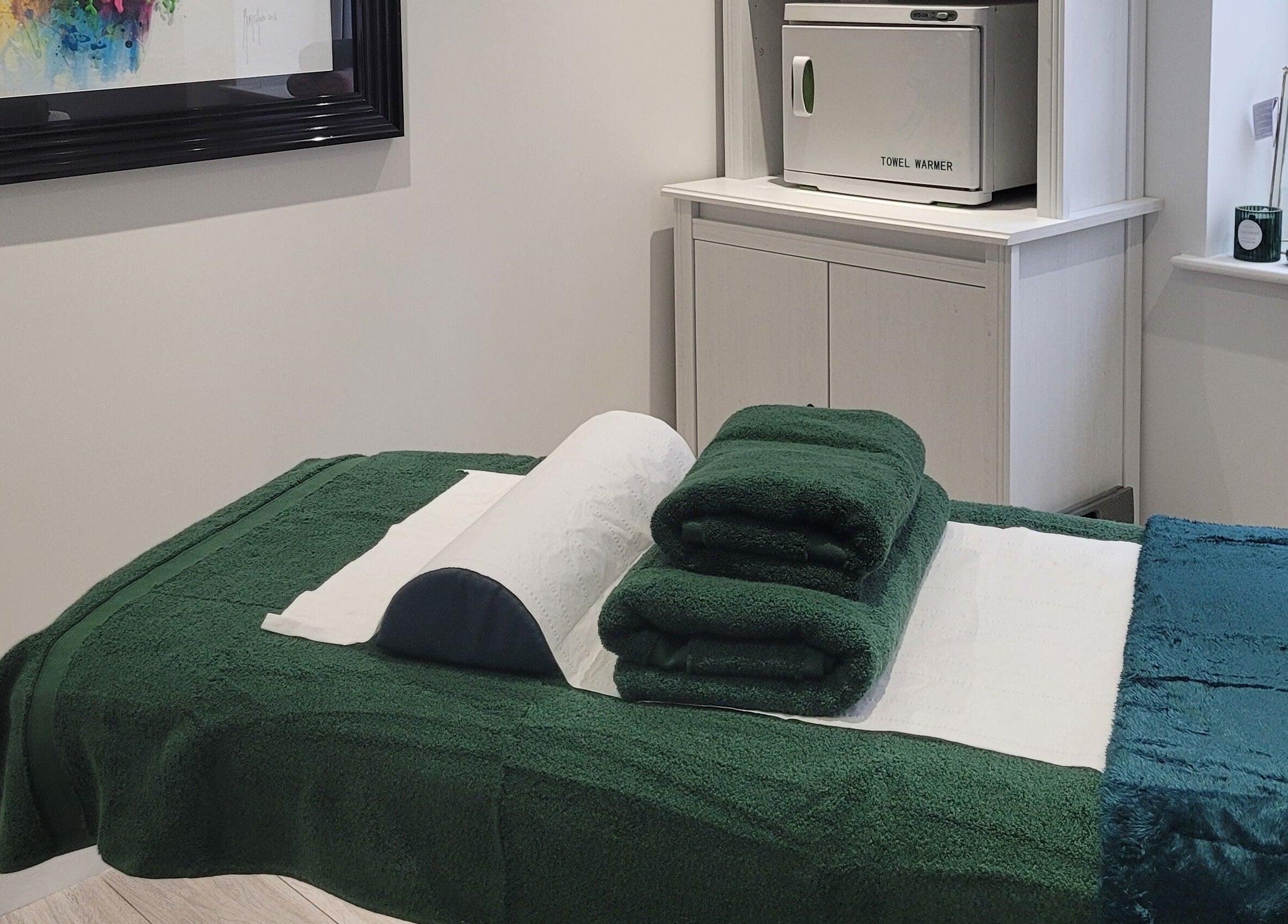 Massage room at Thrive Wellness Centre in Southampton, England, GB with green towels and a towel warmer.