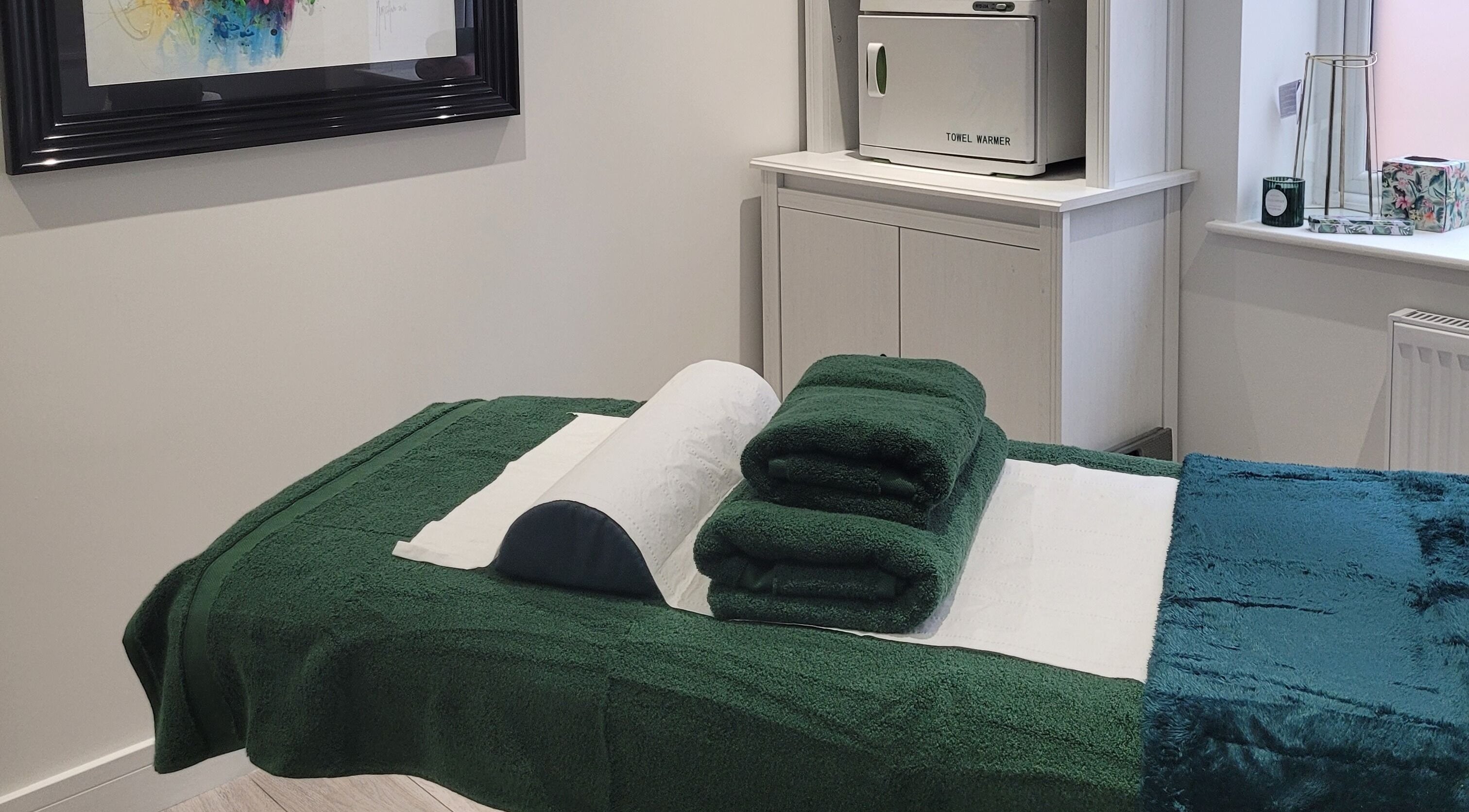 Massage room at Thrive Wellness Centre in Southampton, England, GB with green towels and a towel warmer.