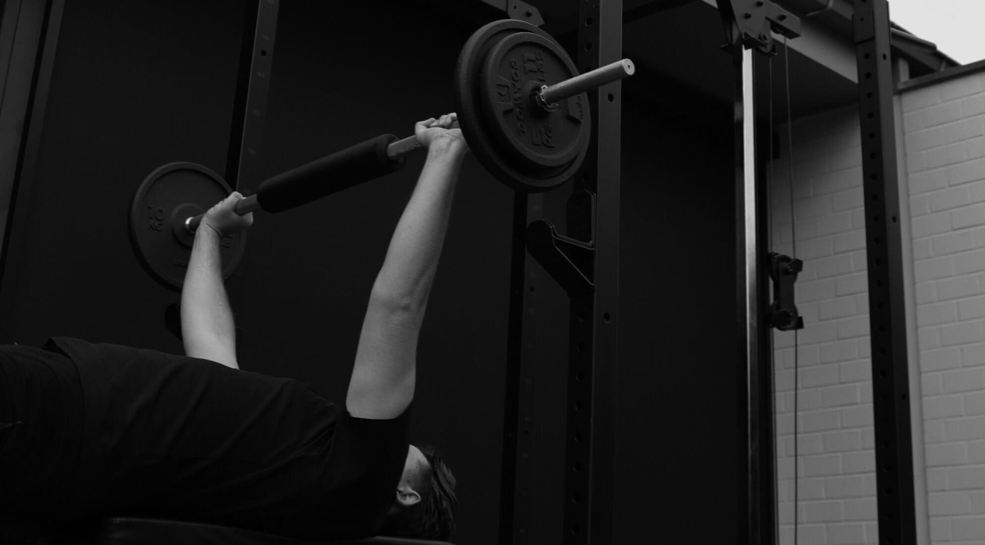Man doet bench press bij Seppt, Eeklo, Vlaams Gewest, BE, met gewichten in een moderne fitnessruimte.