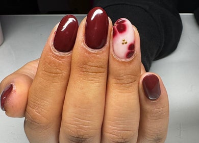 Chic claret nail art at Flo’s Beauty, Thurmaston, England, GB. Rich burgundy polish with floral accent.