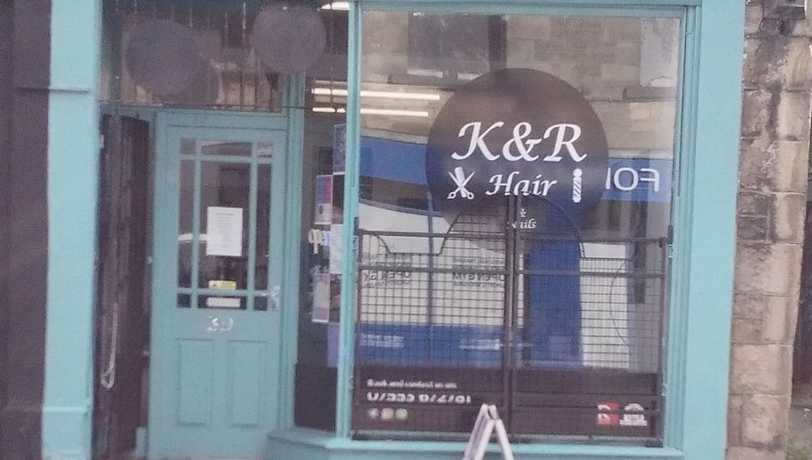Front view of K&R Hair & Nails salon in Lancaster, England, GB with vibrant teal door and window signage.