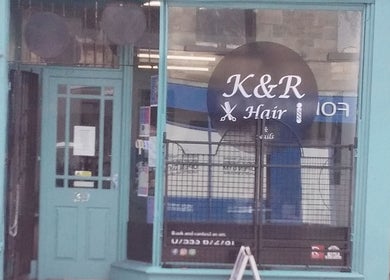 Front view of K&R Hair & Nails salon in Lancaster, England, GB with vibrant teal door and window signage.