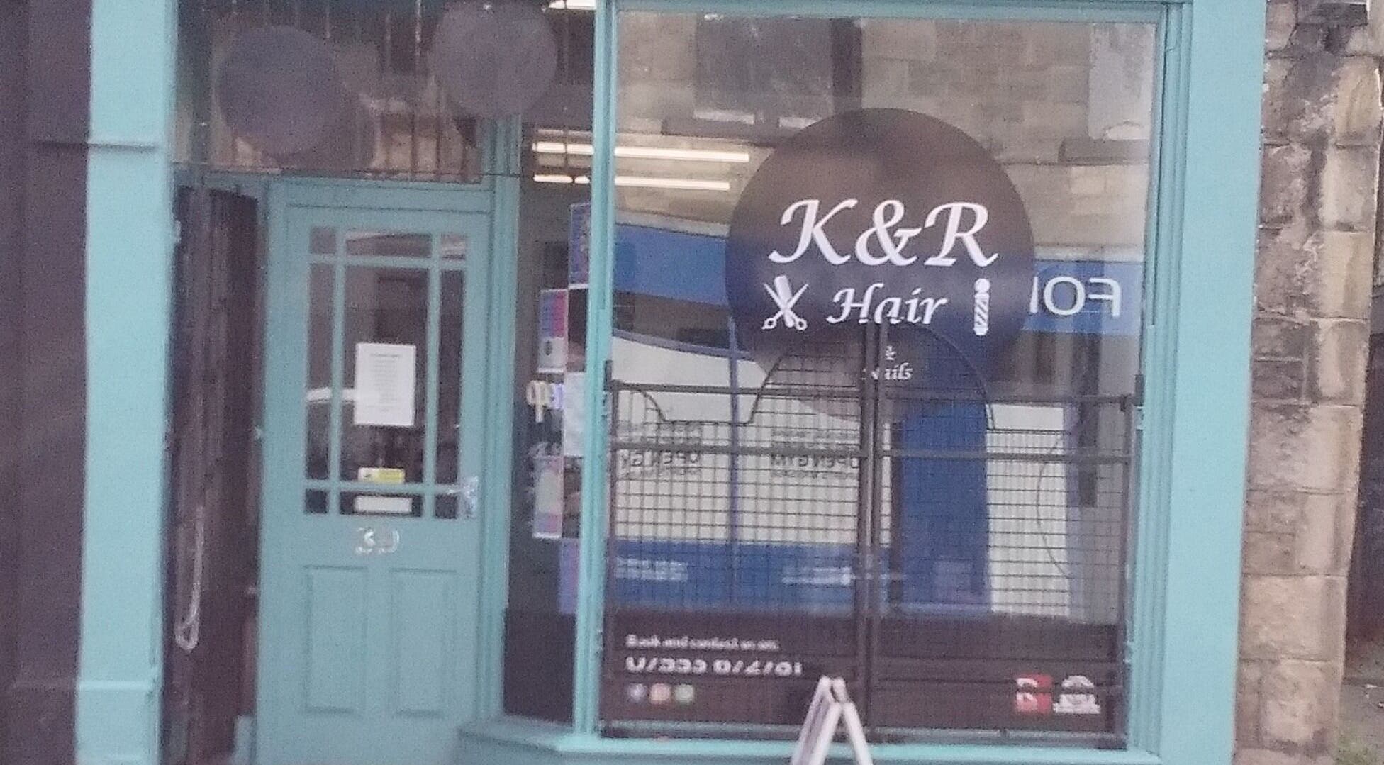 Front view of K&R Hair & Nails salon in Lancaster, England, GB with vibrant teal door and window signage.