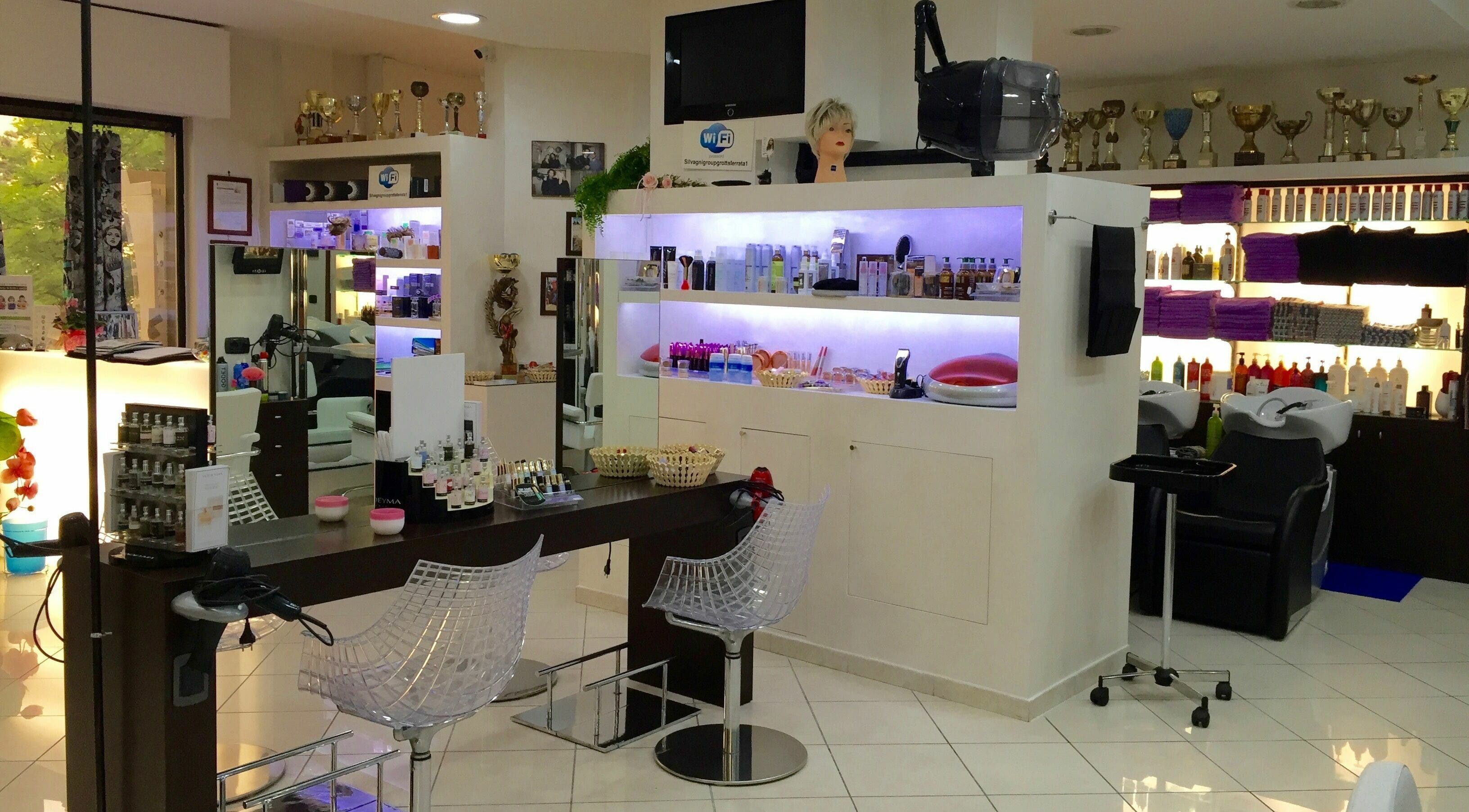 Interni moderni di Silvagni Group Parrucchieri a Grottaferrata, Lazio, IT, con sedie trasparenti e scaffali illuminati.