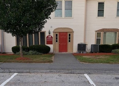 Entrance of Kokoro Therapeutics in Londonderry, New Hampshire, US with red door and lush greenery.